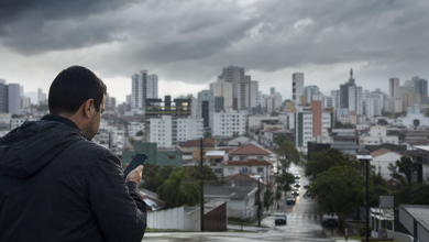 Pessoa usando celular para consultar informações meteorológicas e serviços públicos de emergência em Criciúma