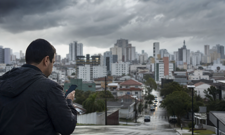 Pessoa usando celular para consultar informações meteorológicas e serviços públicos de emergência em Criciúma