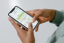 Mãos seguram um celular que exibe um aplicativo de saúde com gráficos e dados.