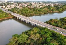 Vista aérea de uma ponte sobre um rio cercado por vegetação em Cuiabá, Mato Grosso.
