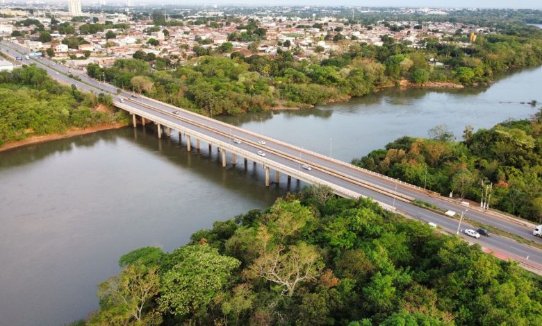 Vista aérea de uma ponte sobre um rio cercado por vegetação em Cuiabá, Mato Grosso.