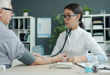 Profissional de saúde verifica a pressão arterial de uma pessoa idosa em uma unidade de atendimento.