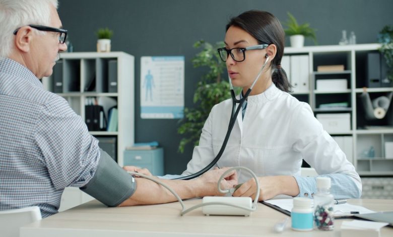 Profissional de saúde verifica a pressão arterial de uma pessoa idosa em uma unidade de atendimento.