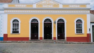 Fachada amarela de um teatro colonial, com janelas em arco e detalhes ornamentais.