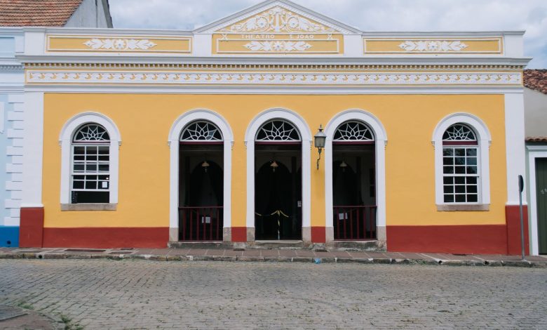 Fachada amarela de um teatro colonial, com janelas em arco e detalhes ornamentais.