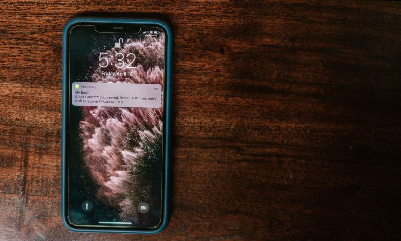 Celular exibindo uma mensagem de alerta bancário sobre uma superfície de madeira