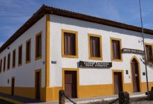 Edifício histórico de arquitetura rústica, com sinalização cultural, sob céu azul.